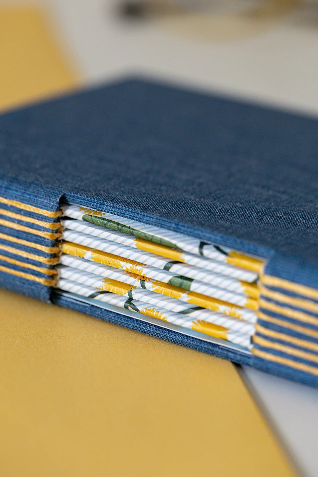 Dettaglio della finestra sul dorso della tecnica di rilegatura Buttonhole, si intravedono i fascicoli autocopertinati con fogli decorati con pattern moderno naturale.