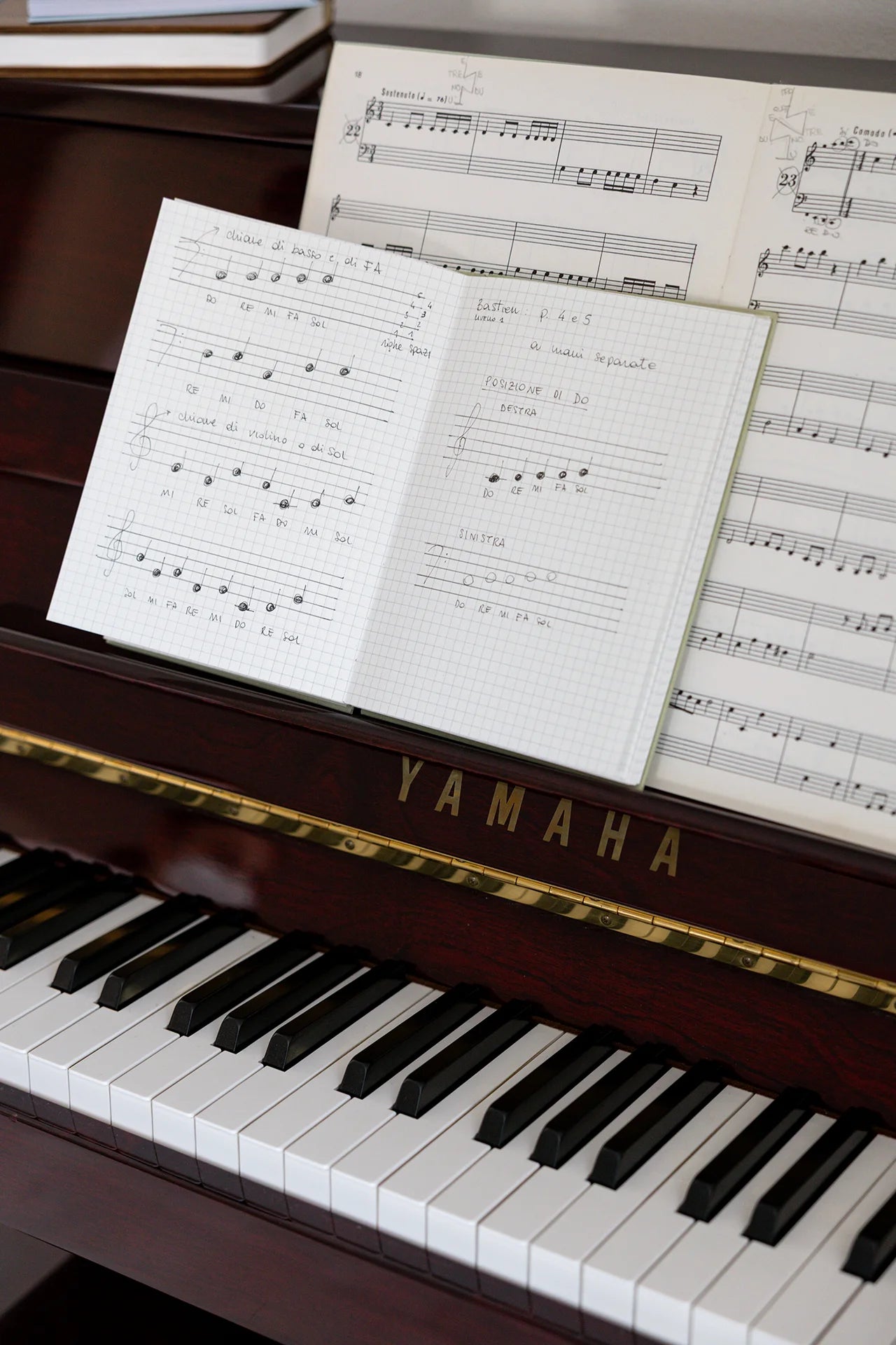 Quaderno artigianale regalato e usato come quaderno di musica con pentagrammi disegnati appoggiato vicino allo spartito su pianoforte.
