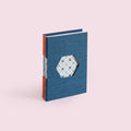 Taccuino A6 rilegato a mano con tecnica Buttonhole, foro esagonale in copertina che lascia vedere le carte decorate dei fascicoli interni, filo arancione fluo decorativo, ideale per regali unici sostenibili.